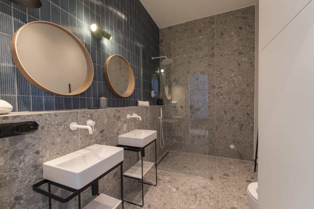 Badezimmer mit Naturstein und runden Spiegeln